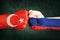 Closeup, flags on fist of Turkey against Syria on a black wall background. Concept of crisis of war and political