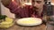 Closeup footage of a cook who is throwing grated cheese on tortilla lying on a plate on wooden table