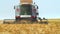 Closeup of forage harvester with slow action collecting wheat and traveling in direction of camera. Farmer on combine