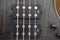 Closeup of four bass strings and black pickups on a grey swamp ash bass body