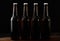 Closeup of four beer bottles isolated on black background