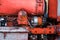 Closeup of four cylinder diesel tractor engine with visible belt rusty tracks hydraulic parts and wiring red paint in