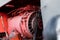 Closeup of four cylinder diesel tractor engine with visible belt rusty tracks hydraulic parts and wiring red paint in sunny autumn