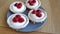 Closeup of four pannacots with raspberries on a gray plate on a light wooden table.