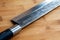 Closeup of a fragment of a kitchen knife on a wooden cutting board. Selective focus