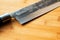 Closeup of a fragment of a kitchen knife on a wooden cutting board. Selective focus