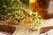 Closeup of fresh blooming shepherd\\\'s purse plant on a table, with a bottle of herbal tincture in the background