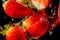 Closeup of fresh and healthy strawberries falling into clear water with big splash on black background. Group of juicy strawberrie