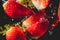 Closeup of fresh and healthy strawberries falling into clear water with big splash on black background. Group of juicy strawberrie