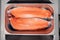Closeup fresh norwegian salmon fillet fish in metal bowl tray on professional restaurant kitchen. Textured background. Concept