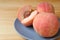 Closeup Fresh Ripe Peaches on Blue Plate with Blurry Cut Peach in the Backdrop