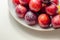 Closeup on fresh and ripe plums on a white ceramic plate