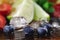 Closeup of fresh succulent blueberry, cubes of ice, lime, lemons and strawberries on a colorful blurred background.