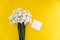 Closeup of fresh white daffodils bouquet with white paper blank note