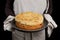 Closeup freshly baked homemade cherry pie with crumbs on top in the hands of the housewife.