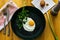 Closeup of fried egg in a black cast-iron pan without oil, sprinkled with salt strag with fresh parsley and garlic. Concept