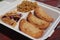 Closeup of the fried fresh and tasty empanadas with rice and plantain chips in the plastic container