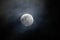 Closeup of a full moon illuminating a cloudy night sky