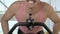 Closeup, funny bald man is training on an exercise bike, smiling