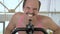 Closeup, funny bald man is training on an exercise bike, smiling