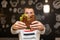 Closeup funny blurred protrait of young man hold bitten sandwich by his two hands. Sandwich in focus. dark background