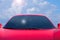 Closeup of generic red sports car hot rod automobile with clouds background