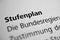 Closeup of the german word Stufenplan written in bold font surrounded by blurred words