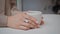 Closeup girl hands holding mug with hot beverage in cafe. Unknown woman taking