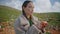 Closeup girl peeling apple on green hill. Contemplative traveler rest mountains