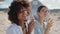 Closeup girls clinking glasses on summer beach picnic. Happy curly woman posing