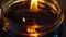 A closeup of a glass jar filled with a dark viscous liquid with a small flame burning at the top. This represents the