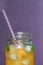 Closeup Glass jars of orange juice with ice and kumquat on violet background