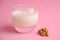 Closeup of a glass of liquid yogurt with walnuts isolated on a pink background