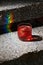 Closeup glass of negroni cocktail with ice at stairs with rainbow flare background. Vertical image with copyspace