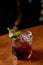 Closeup of a glass of negroni cocktail with lime on a bar counter