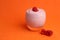 Closeup of a glass of sweet yogurt with a fresh raspberry on top on an orange background