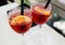 Closeup glasses of cocktail decorated with oranges on the table. Colorful pink soft drinks with ice and straws in a cafe