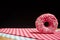 Closeup of a glazed fresh donut on chequered tablecloths on a cutting board