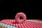 Closeup of a glazed fresh donut on chequered tablecloths on a cutting board