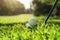 closeup golf club and golf ball on green grass wiht sunset