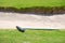 Closeup of a golf course sand trap and rake