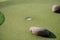 Closeup of a golfing club with rocks, grass and the hole for the golf ball