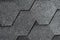 Closeup of gray asphalt roof shingles texture. Roof covered by hexagonal soft shingles or tiles. Abstract background