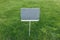 Closeup gray metal sign at green grass background, nameplate with a space for your text. Horizontal banner