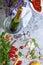 Closeup of a gray table with plate, champagne, tomatoes, asparagus, glasses, corkscrew, beans on a gray background.