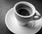 Closeup grayscale shot of a cup of just made  espresso placed on the table