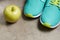 Closeup on green apple and sneakers on floor
