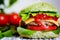 Closeup green burger with artificial meat, fresh vegetables on wooden background. Vegetarian food