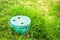 Closeup of green plastic pipe with cover on green grass lawn