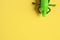 Closeup of a green plastic toy grasshopper on a yellow background